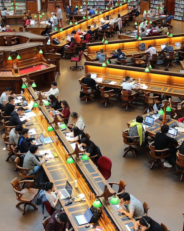 Bovenaanzicht van rijen studerende jongeren in een bibliotheek. Bovenaanzicht van rijen studerende jongeren in een bibliotheek.