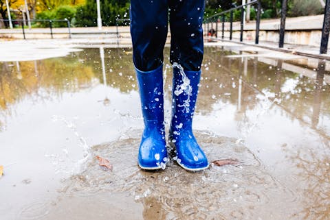 Tijdens storm Benjamin viel de waterstand aan de kust mee. blauwe laarzen stampen in een plas
