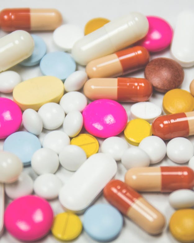 Een stapel pillen en capsules op een wit oppervlak.