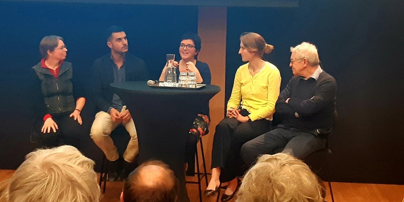 Vijf sprekers op een podium. Mirjam Ernestus, Khalid Mourigh, Sharon Unsworth, Merel Keijzer en Roeland van Hout.