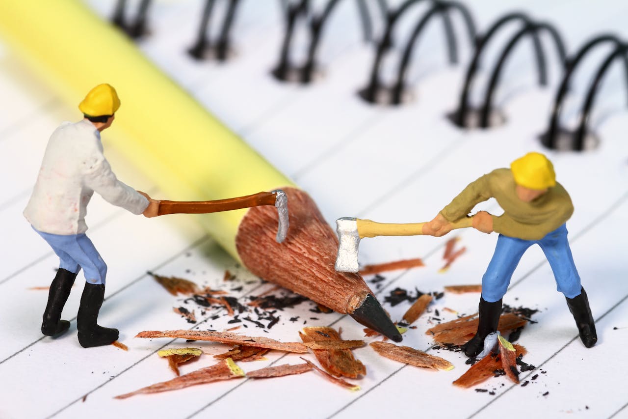De kwaliteit van het onderwijs verschraalt. Twee miniatuurmannetjes slopen samen een potlood met een bijl