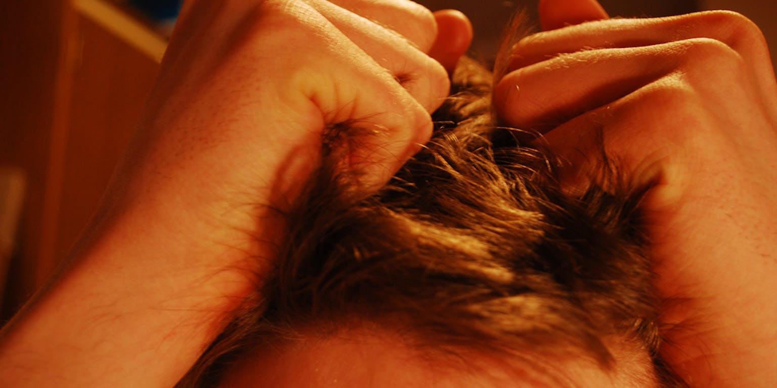 Een man zit met zijn handen in het haar.