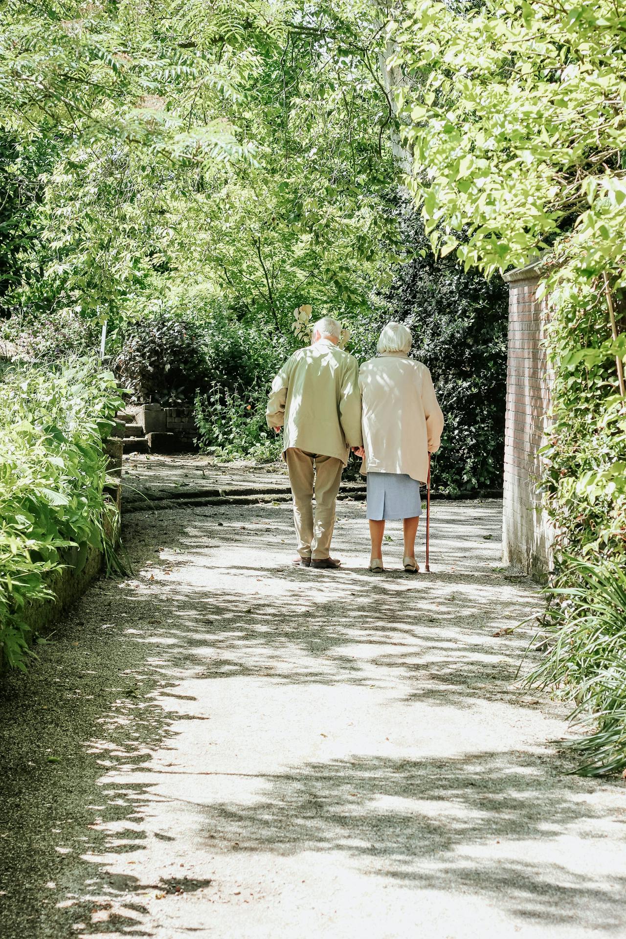 Een ouder echtpaar loopt over een pad in een park.