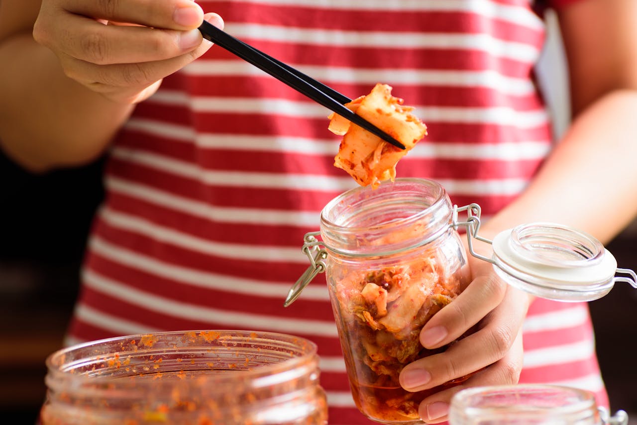 Vrouw eet kimchi uit een glazen pot