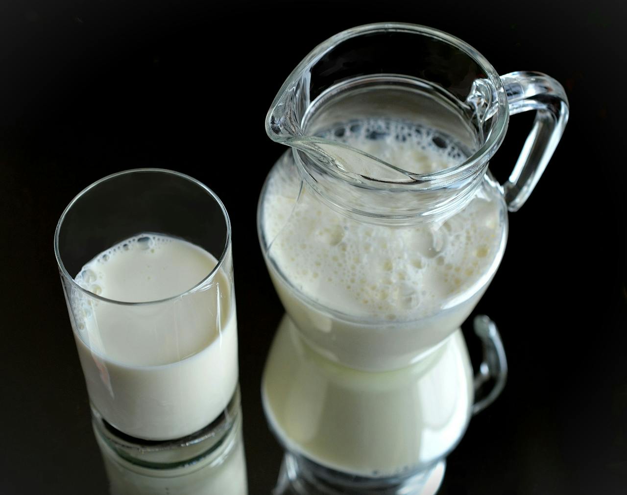 Een melkkan naast een glas melk.