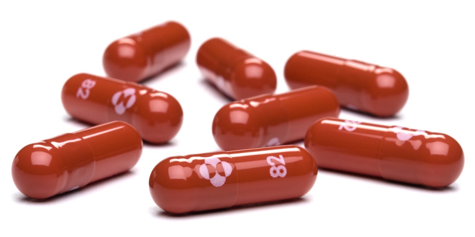 Een groep rode pilcapsules op een witte achtergrond.