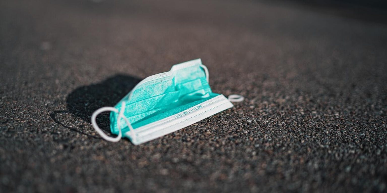 Een mondmasker dat op de weg ligt