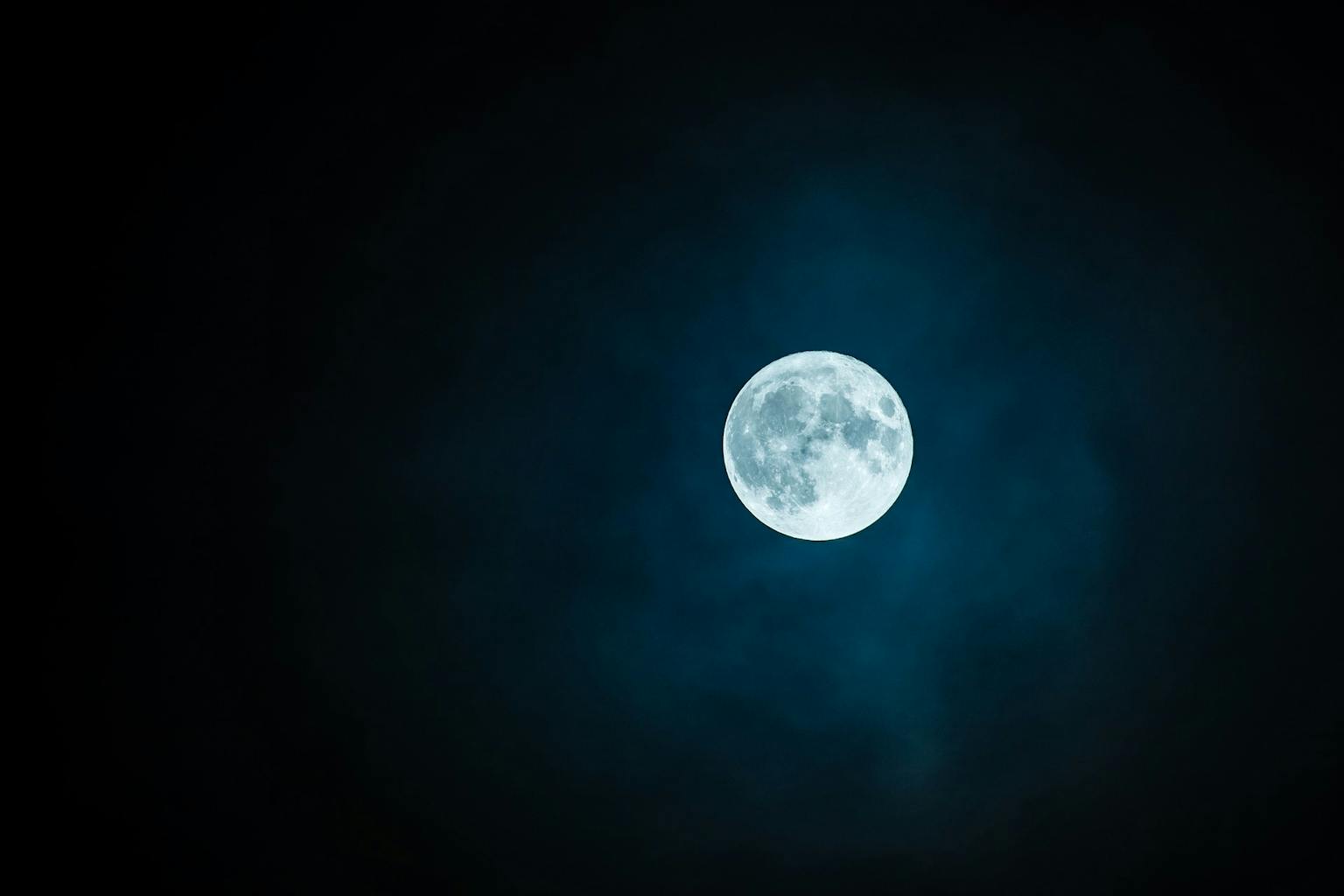 Aan de donkere hemel is een volle maan te zien.
