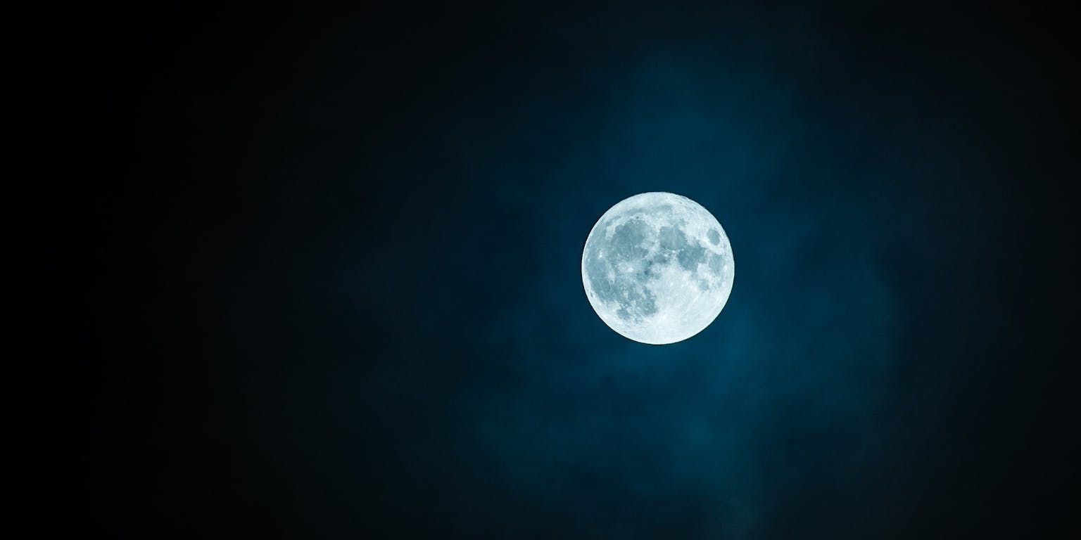 Aan de donkere hemel is een volle maan te zien.