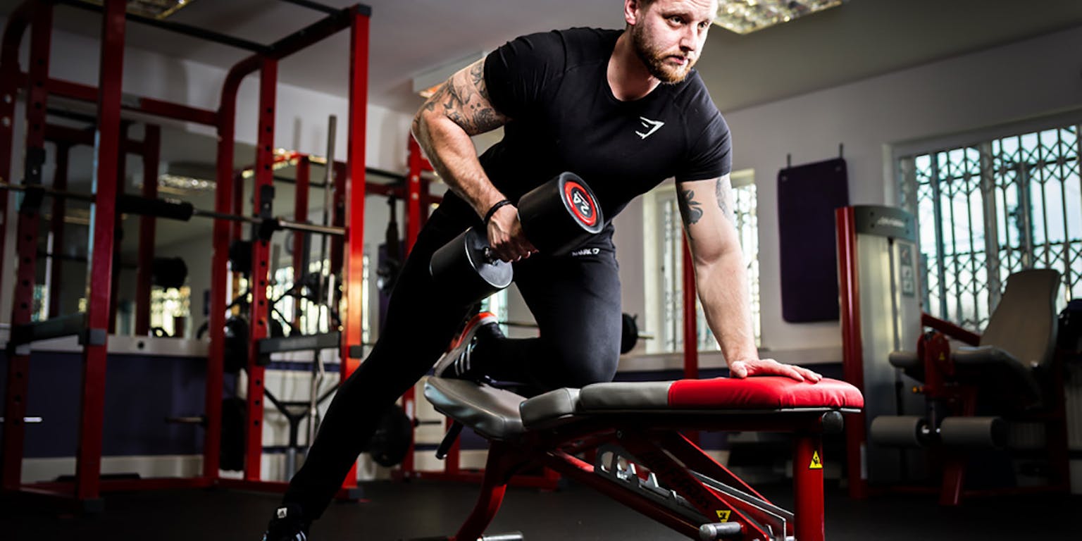 Een man die aan gewichtheffen doet in een sportschool.