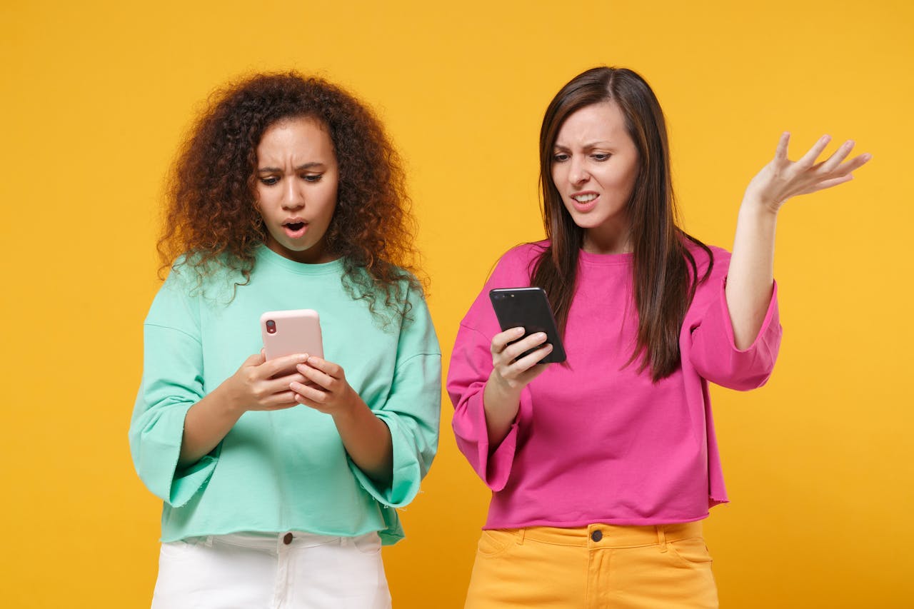 Twee jonge vrouwen kijken boos naar hun mobieltje