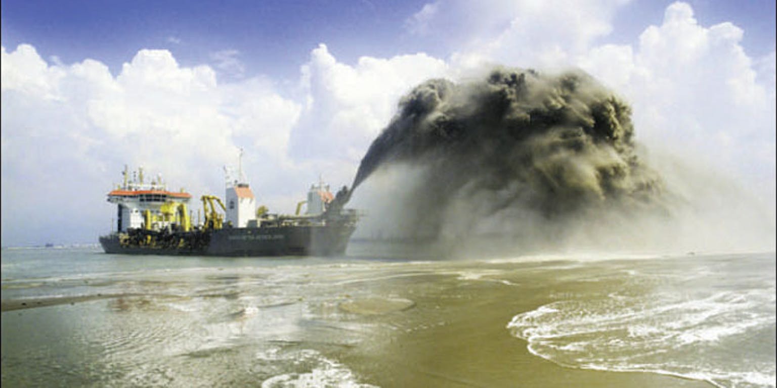 Er ligt een schip in het water. Het schip spuit zand op.