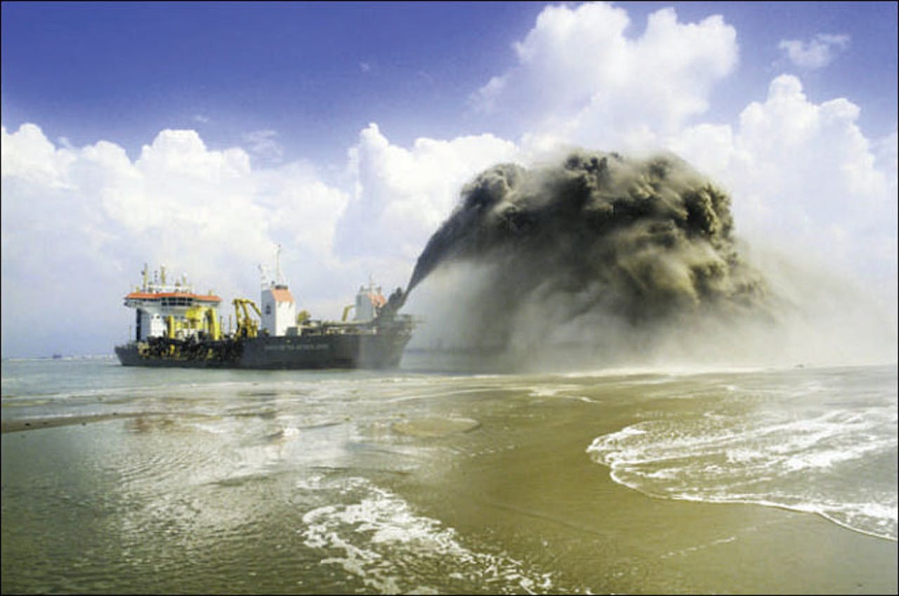 Er ligt een schip in het water. Het schip spuit zand op.