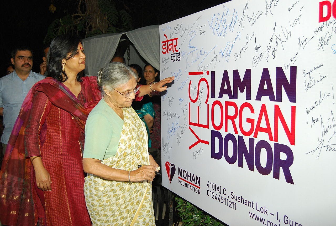 Sheila Dikshit, een politica uit India, laat door het zetten van haar handtekening zien dat ze achter orgaandonatie staat. De Indiase politica Sheila dixit zet haar handtekening op een bord voor orgaandonatie.