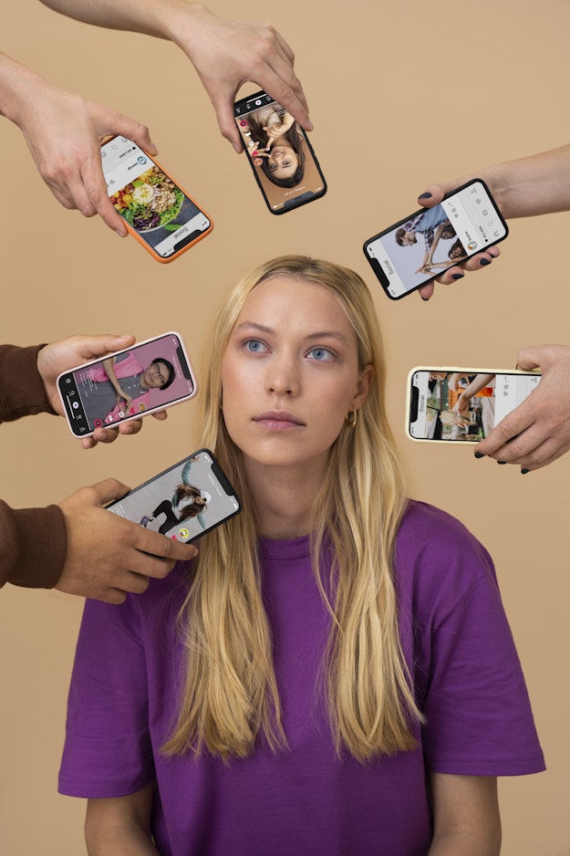 Vrouw omringd door mobiele telefoons waarop social media-pagina's zijn te zien.