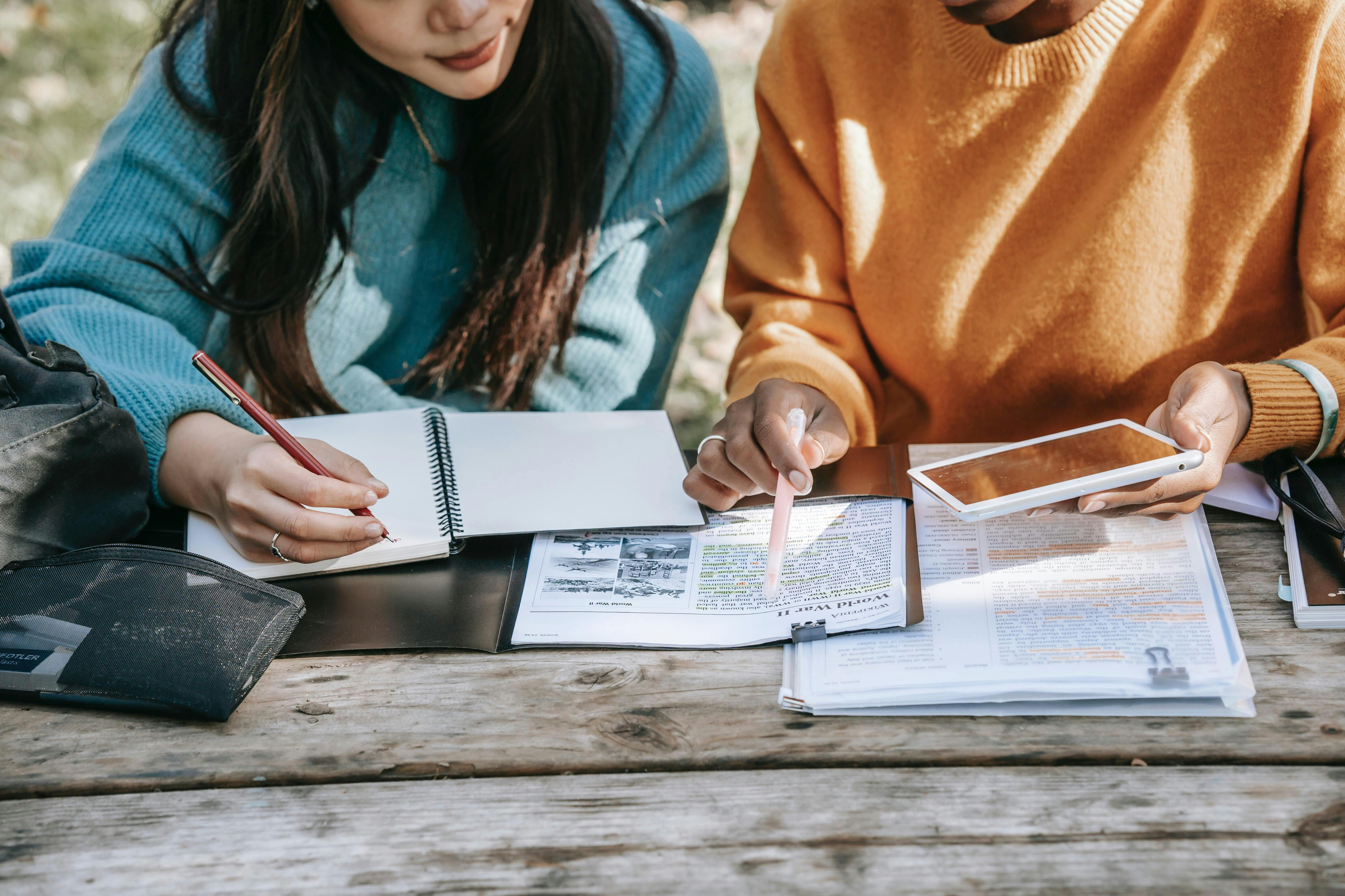 Een groep mensen zit aan een picknicktafel en leest samen een document.