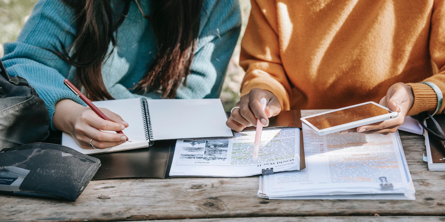 Een groep mensen zit aan een picknicktafel en leest samen een document.