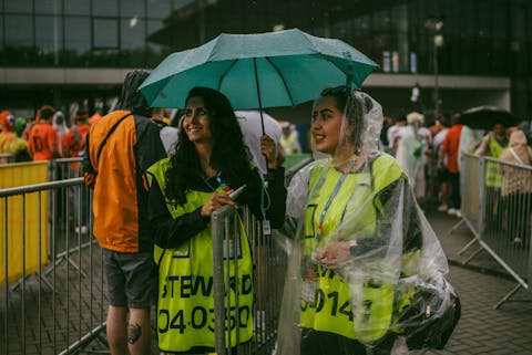 Met name op de langere termijn worden weersvoorspellingen steeds onbetrouwbaarder. Twee stewards die tijdens een regenachtige dag, buiten bij een evenement staan.