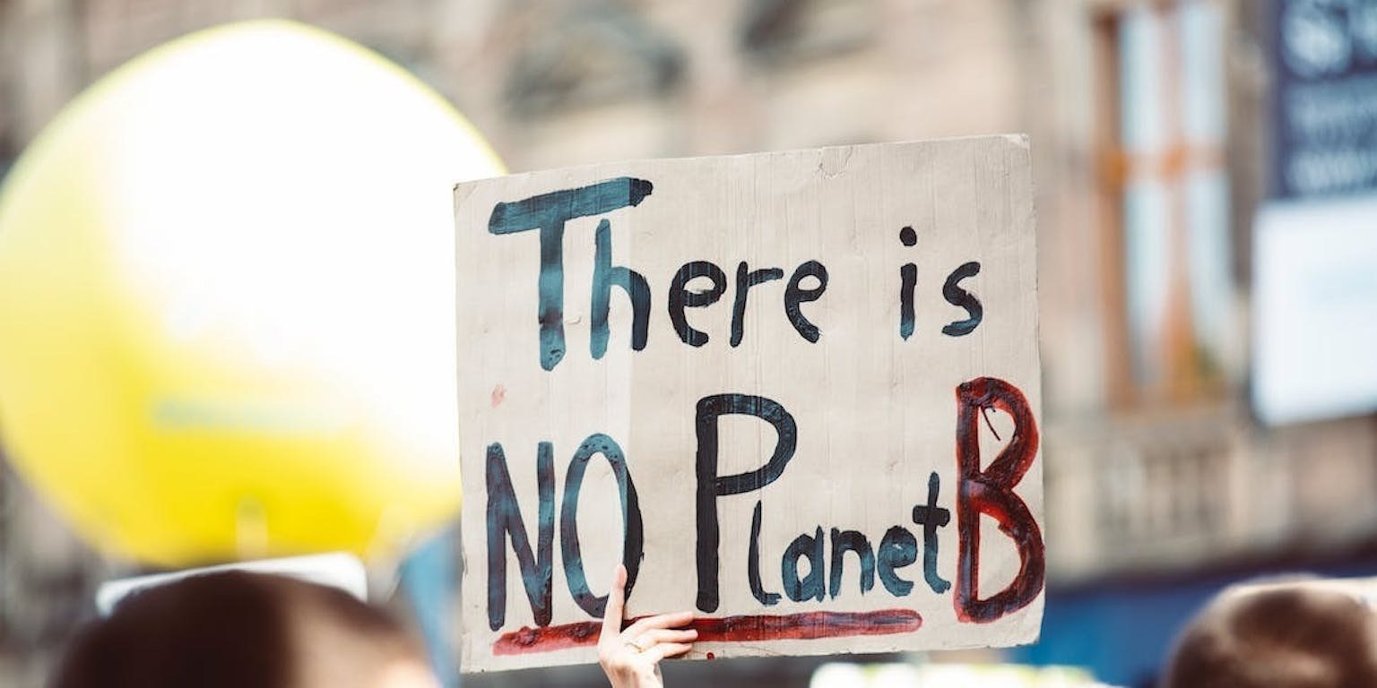 Iemand houdt een bordje omhoog met daarop de tekst 'There is NO Planet B.