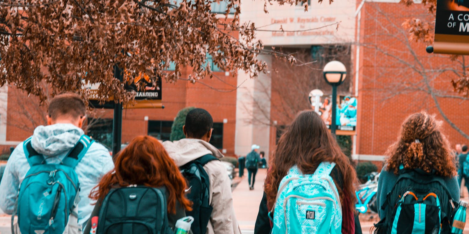 Een groep studenten loopt met rugzakken door de straat.