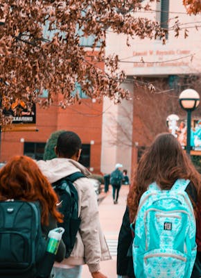 Een groep studenten loopt met rugzakken door de straat.