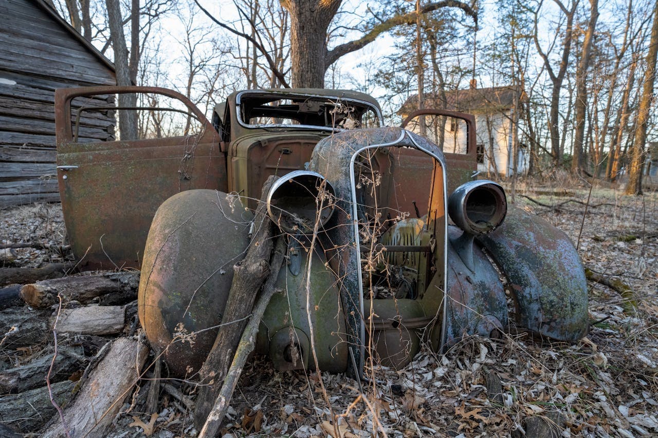 Was de uitvinding van de auto vooruitgang, of begin van het einde? Kapotte, doorgeroeste onbruikbare auto in landelijk landschap