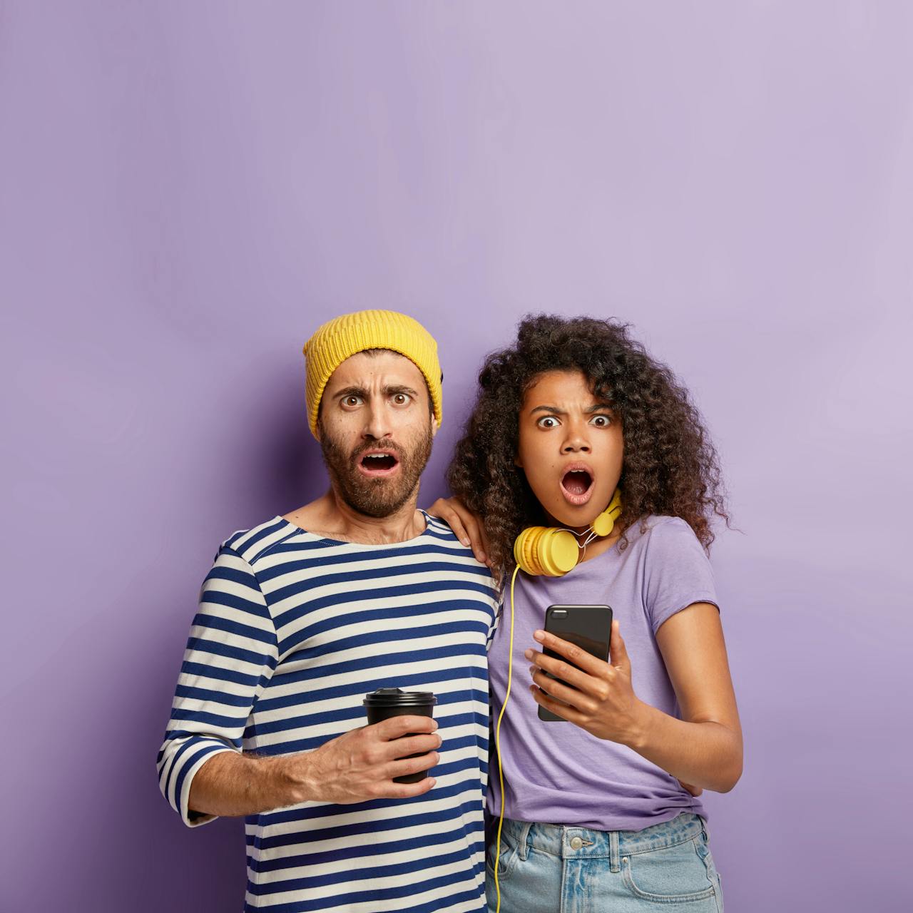 Jonge man en vrouw kijken geshockeerd weg van hun telefoon