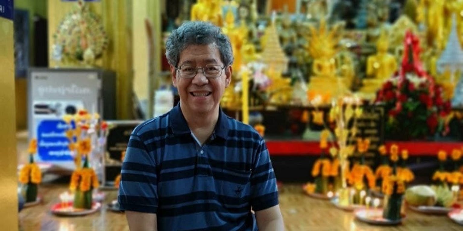 Een man zit op de grond voor een tempel.