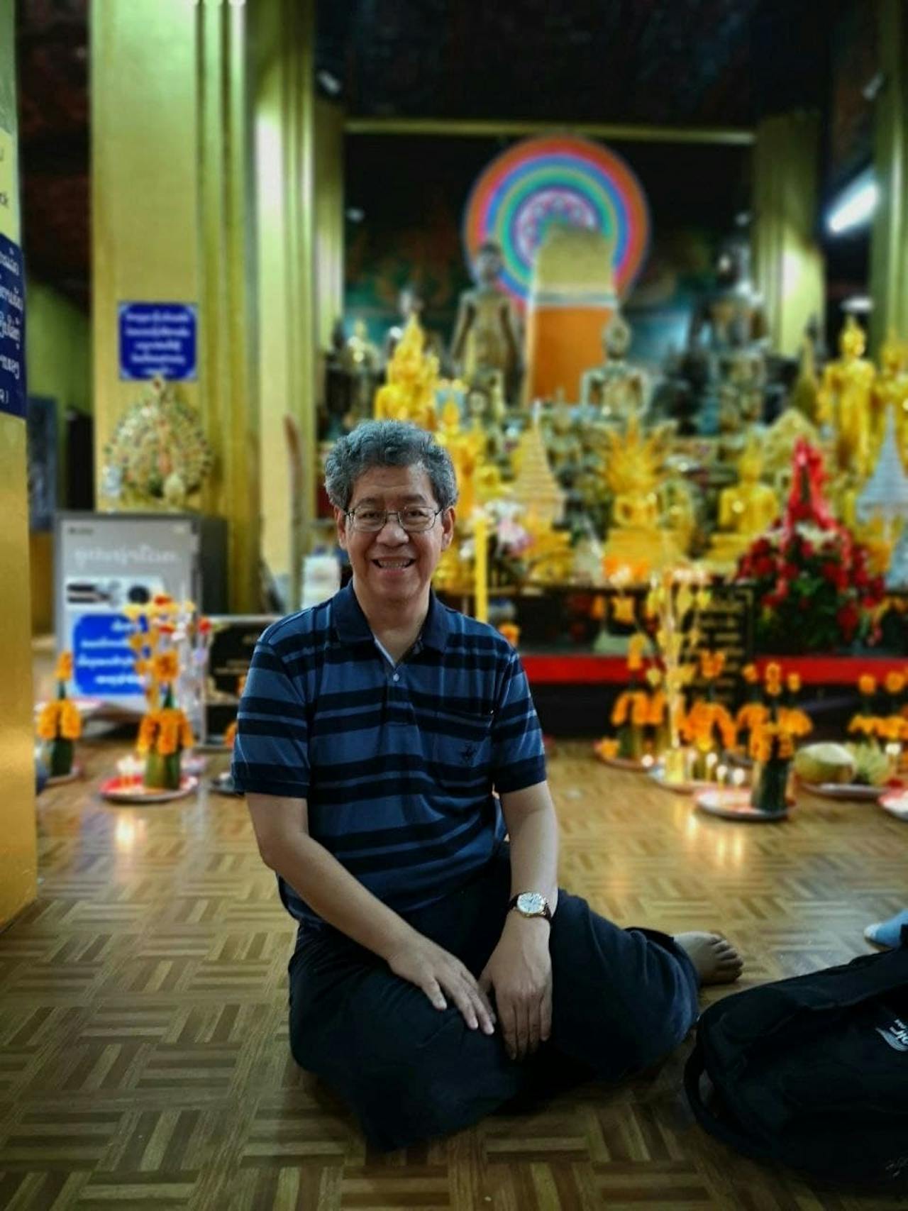 Een man zit op de grond voor een tempel.