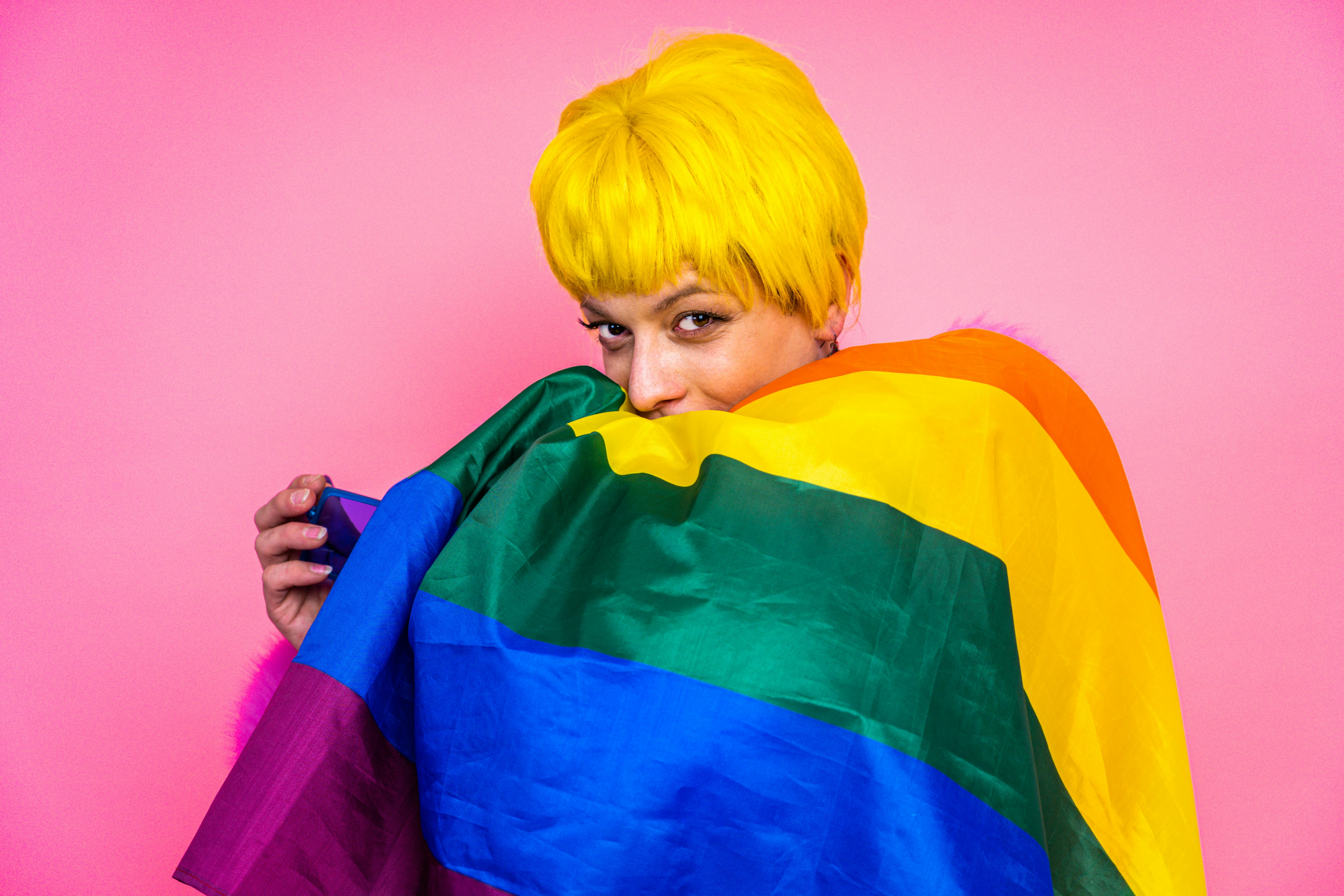 persoon met geel kort haar en regenboogvlag