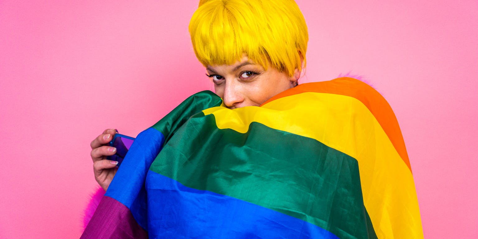 persoon met geel kort haar en regenboogvlag