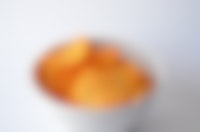 Aardappelchips in een witte kom op een witte achtergrond.