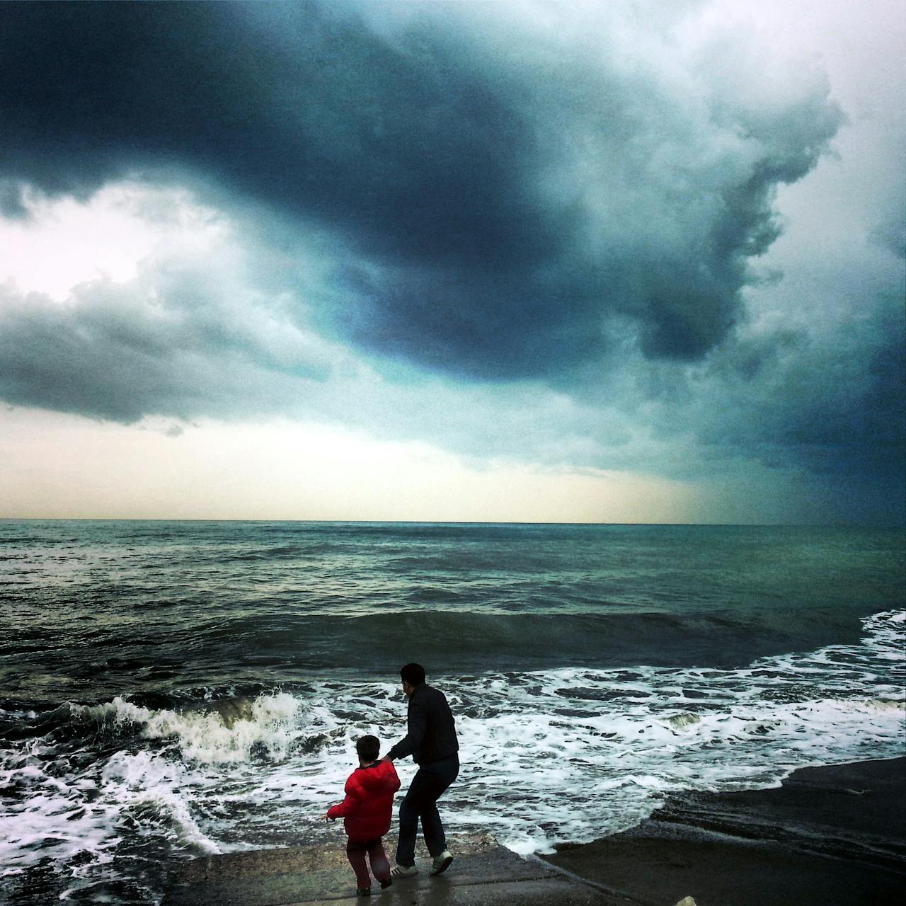Een storm krijgt een naam als het KNMI code oranje of rood uitgeeft voor harde windstoten. een ouder met kind staan aan zee tijdens een dreigende storm
