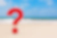 een rood vraagteken op het strand met zee op de achtergrond