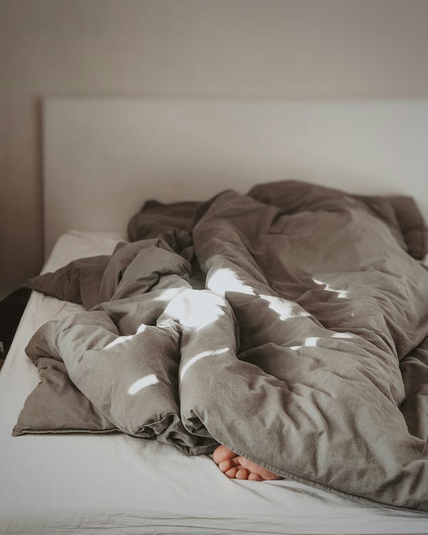 Iemand ligt onder de dekens in bed, alleen de tenen steken uit. Iemand ligt onder de dekens in bed, alleen de tenen steken uit.
