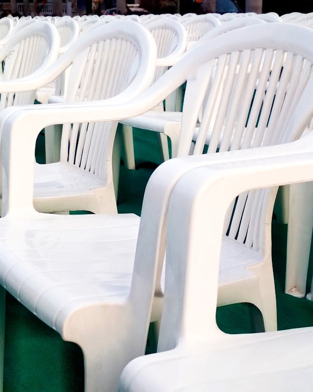 Rijen tuinstoelen van wit plastic op een groene ondergrond. Rijen tuinstoelen van wit plastic op een groene ondergrond.