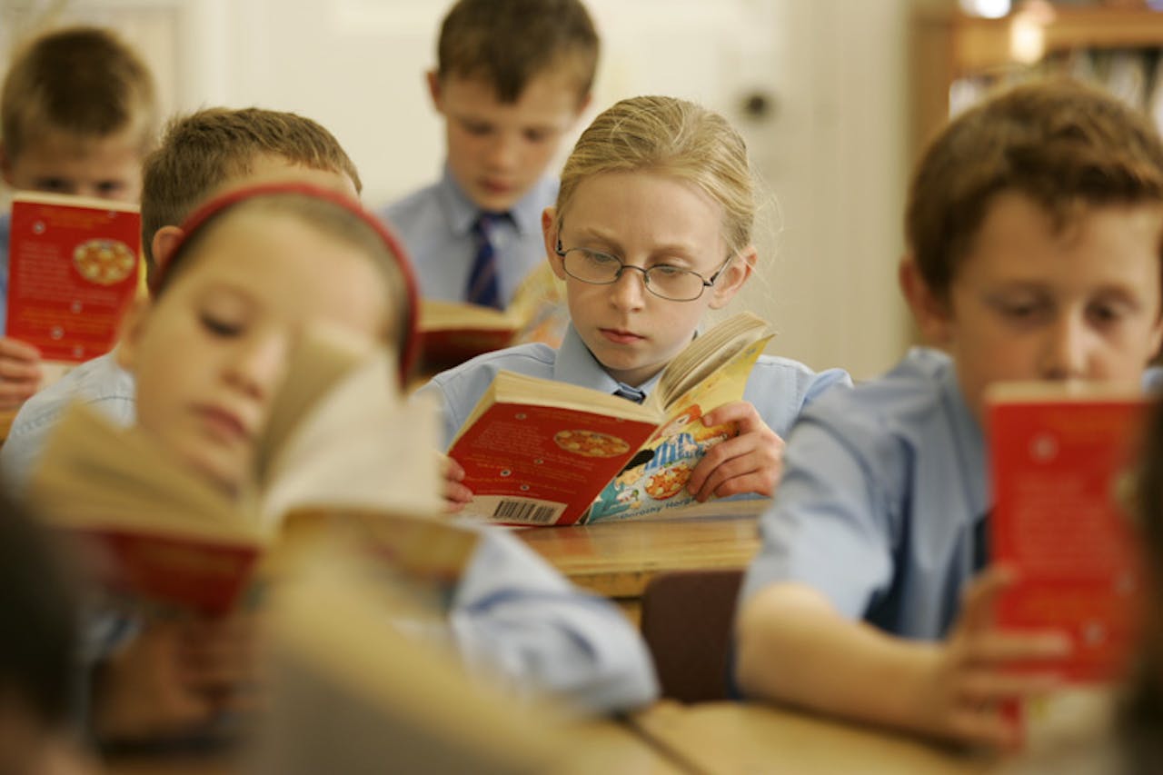 Een groep kinderen die boeken lezen in een klaslokaal.
