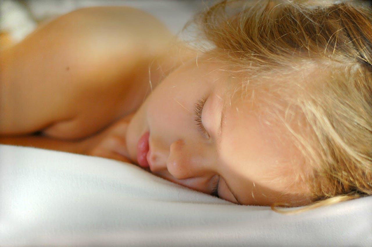 Een jong meisje slaapt op een bed.