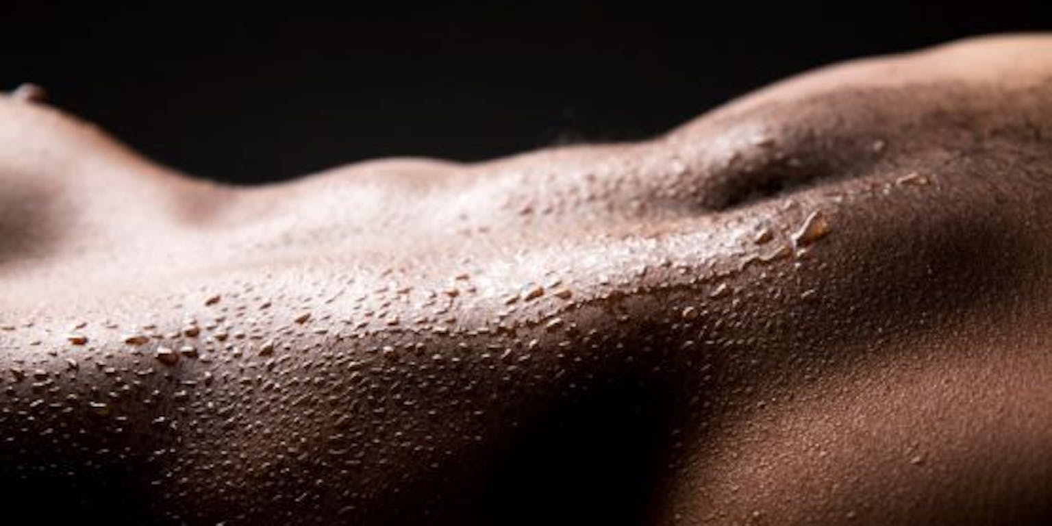 Het torso van een man met zweetdruppels erop.