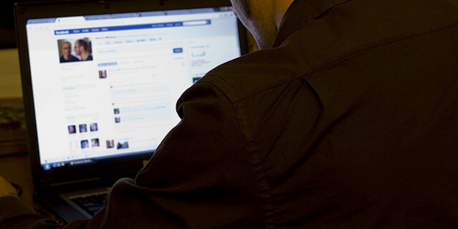 Een persoon zit achter zijn laptop op Facebook.