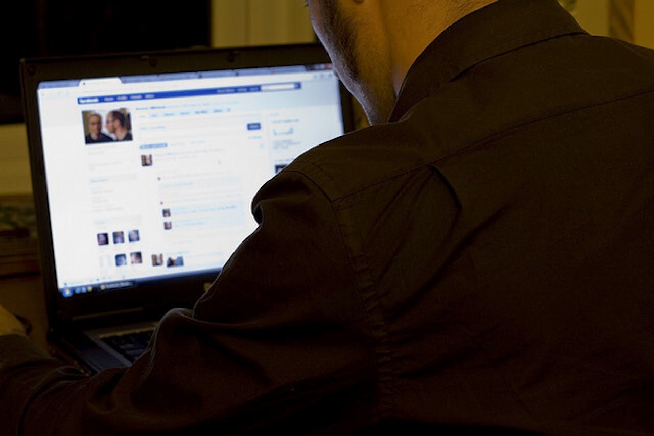 Een persoon zit achter zijn laptop op Facebook.