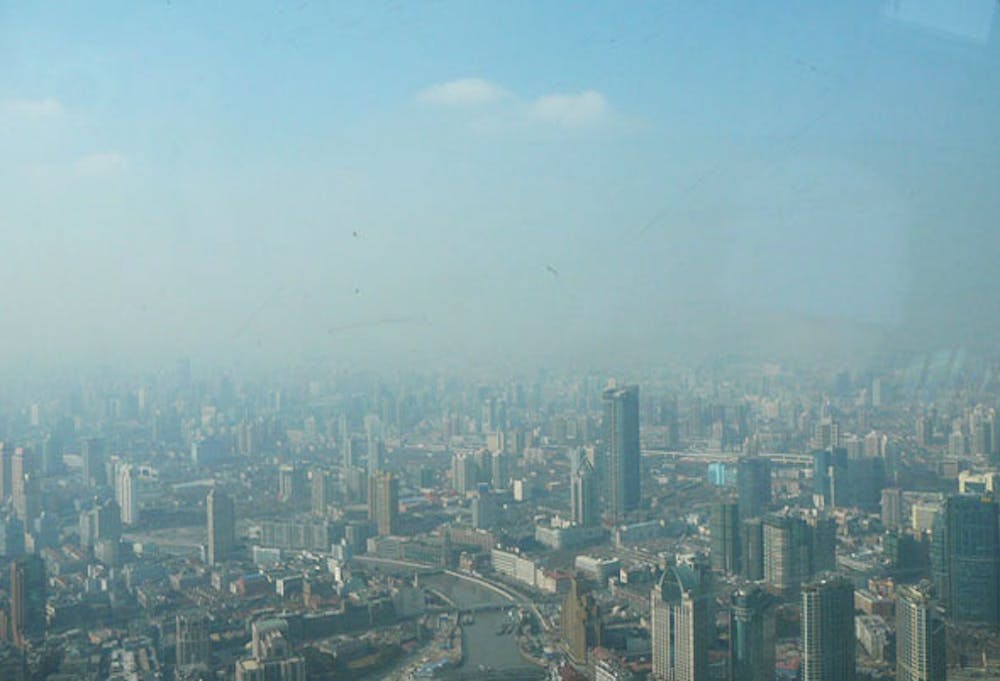 <p>Een foto van de binnenstad van Shanghai genomen vanaf één van de hoogste torens ter wereld, de Oriental Pearl Tower met een maximale hoogte van 468 meter. In het oog vallend is het deken van smog met onder meer zwarte aerosolen over de stad; daarboven is gewoon blauwe lucht te zien.</p>