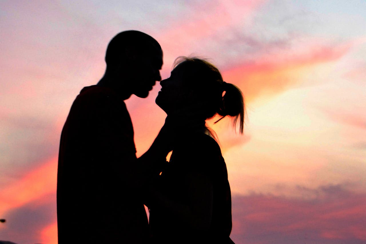 Silhouet van een man en vrouw die kussen bij zonsondergang.