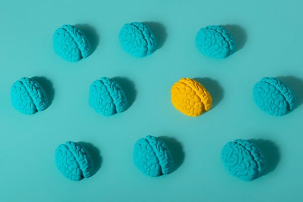 Een blauw vlak met tien kunstmatige hersenen; negen zijn blauw en één is geel.