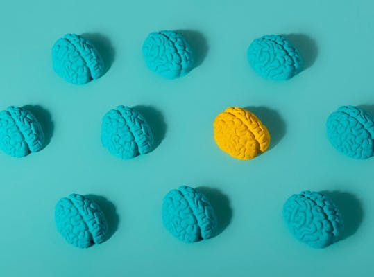 Een blauw vlak met tien kunstmatige hersenen; negen zijn blauw en één is geel.