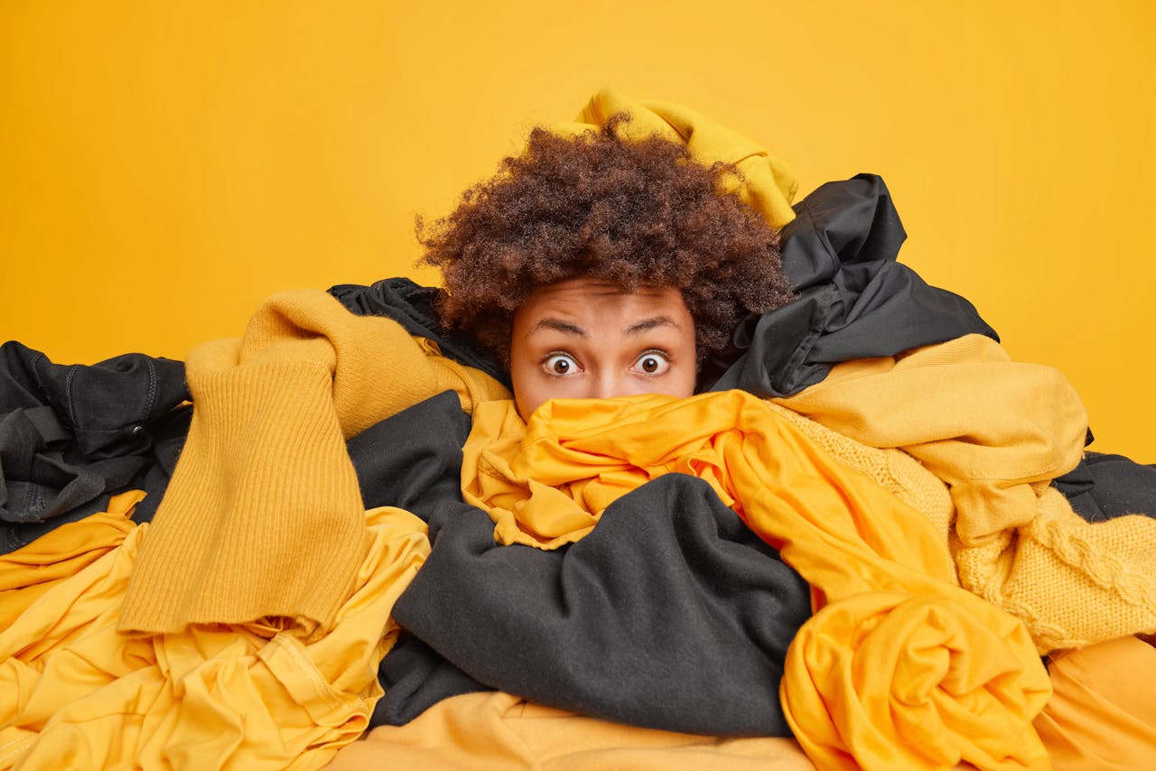 Deze zomer staat weer een berg kleding met micro-trends voor je klaar. Jonge vrouw verzuipt in de kledingstukken
