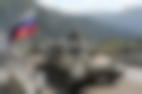 Russische tanks op een weg met bergen op de achtergrond.