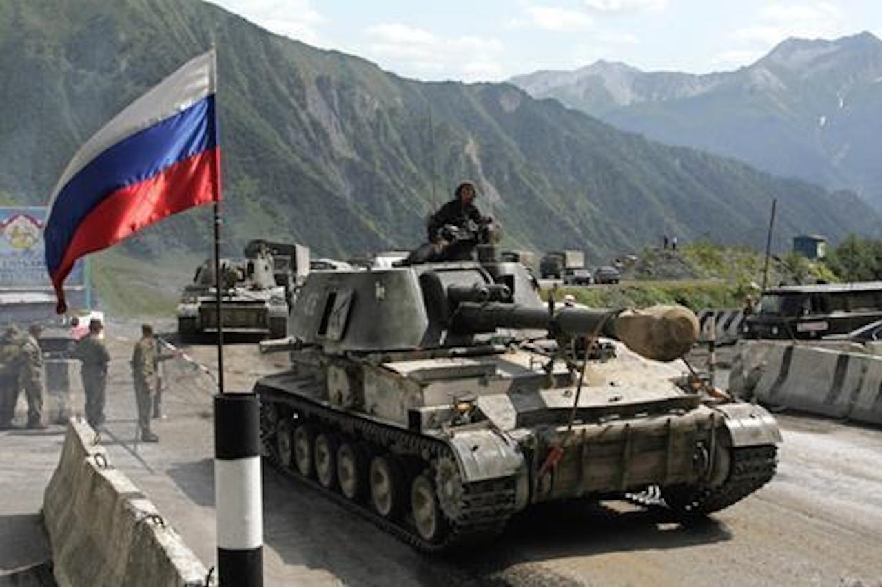 Russische tanks op een weg met bergen op de achtergrond.