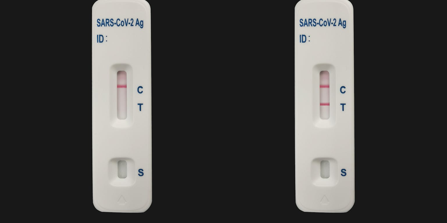 Twee coronatesten naast elkaar. Een negatieve test en een positieve test.
