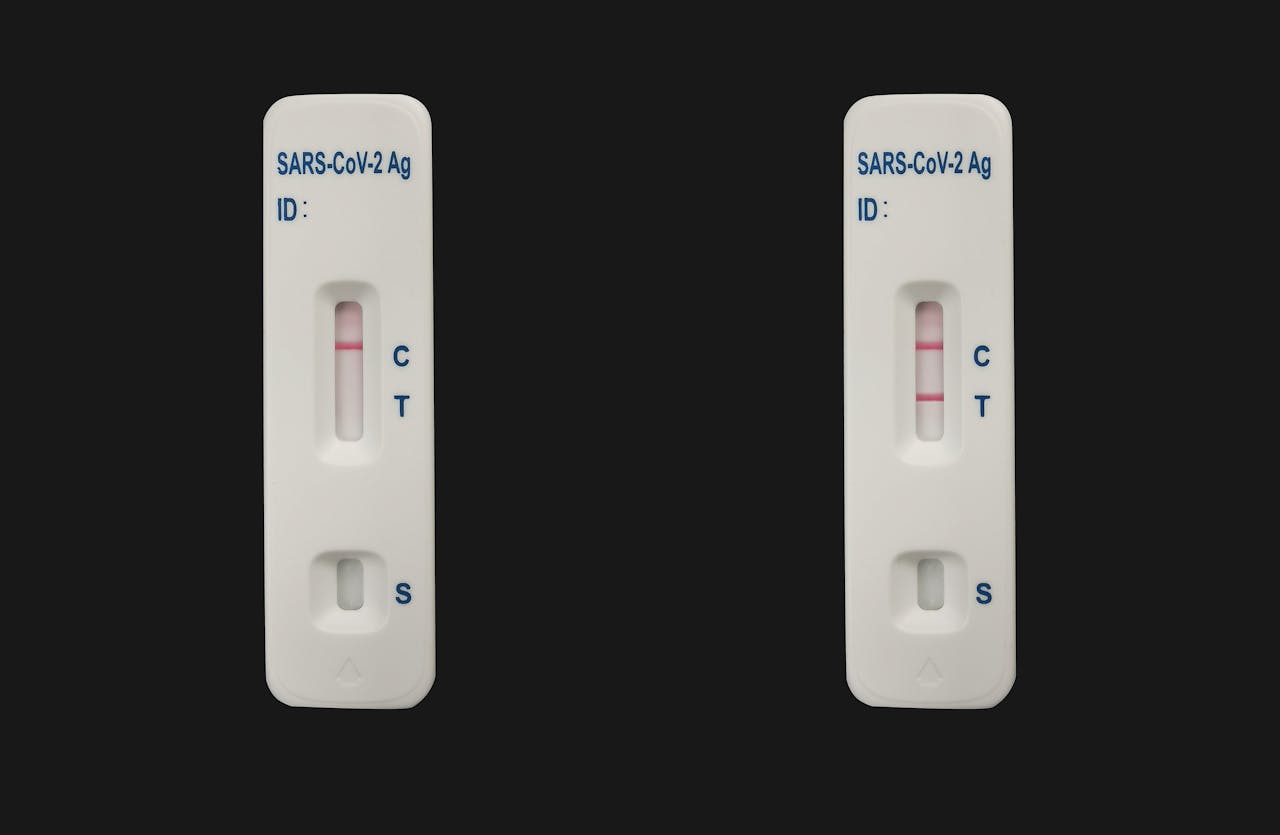 Twee coronatesten naast elkaar. Een negatieve test en een positieve test.